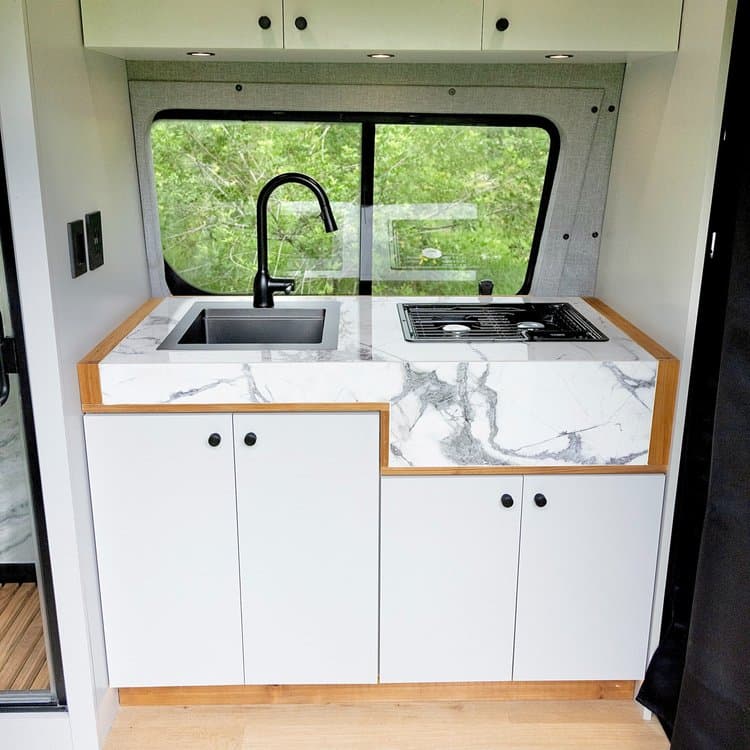 Custom War Horse van kitchen with stone surface and light cabinetry
